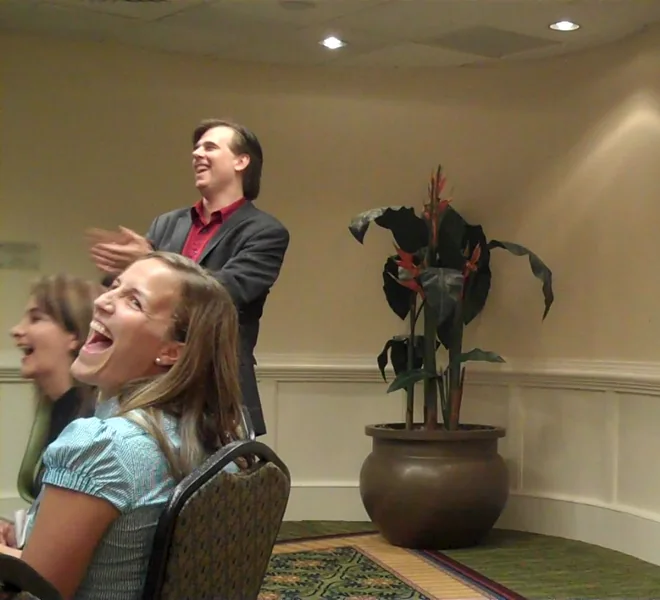 A participant laughing during a workshop while Toby facilitates in the background.
