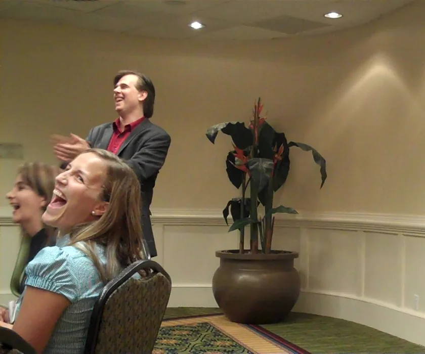 A participant laughing during a workshop while Toby leads the activity behind her.