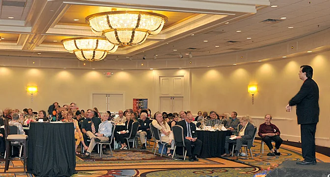 Toby leading a session for a large business audience in a hotel meeting room.