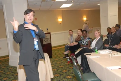 Toby leading a small business workshop while participants watch from nearby tables.